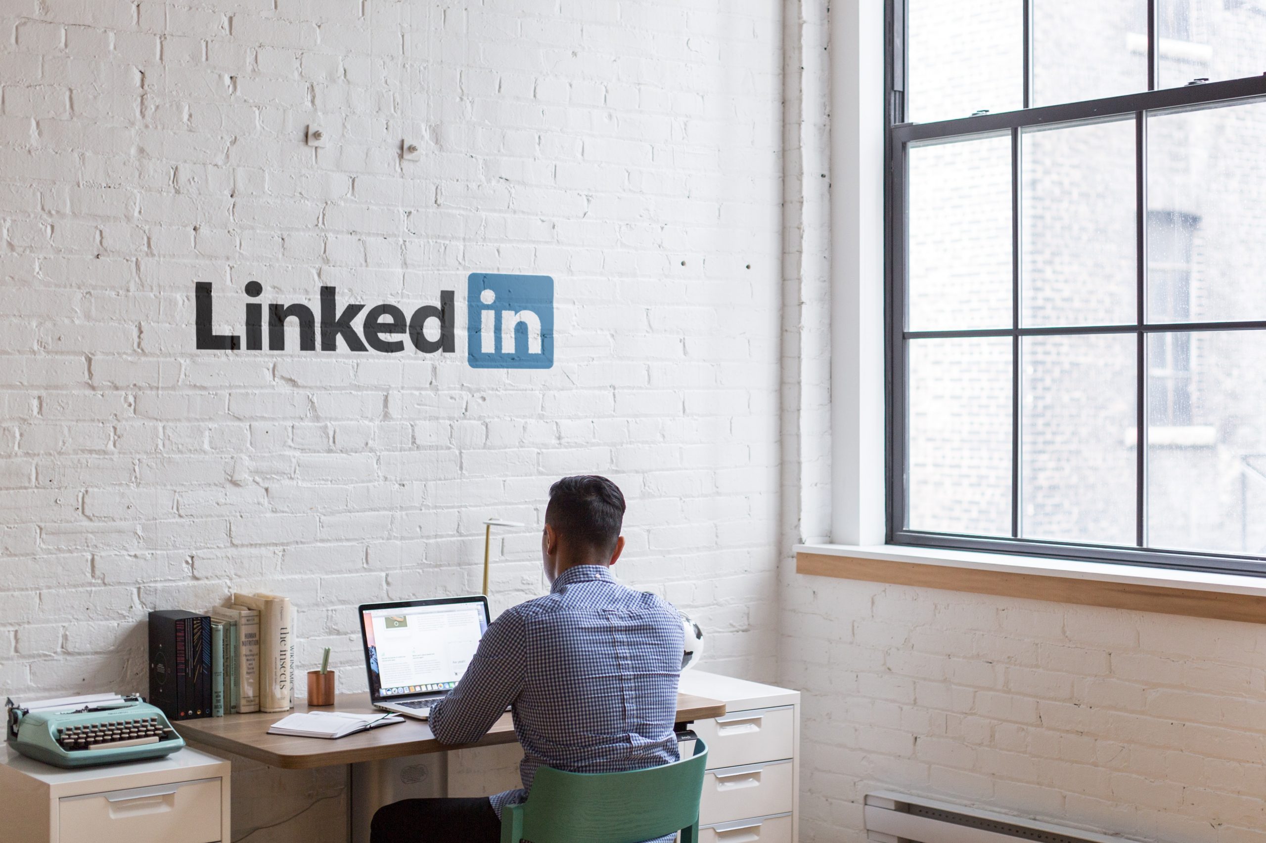 A man working in an office with a linkedin logo on the wall.