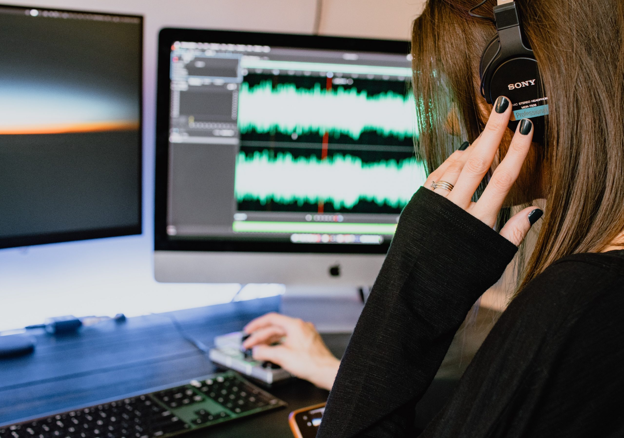 A woman editing a podcast on a computer.