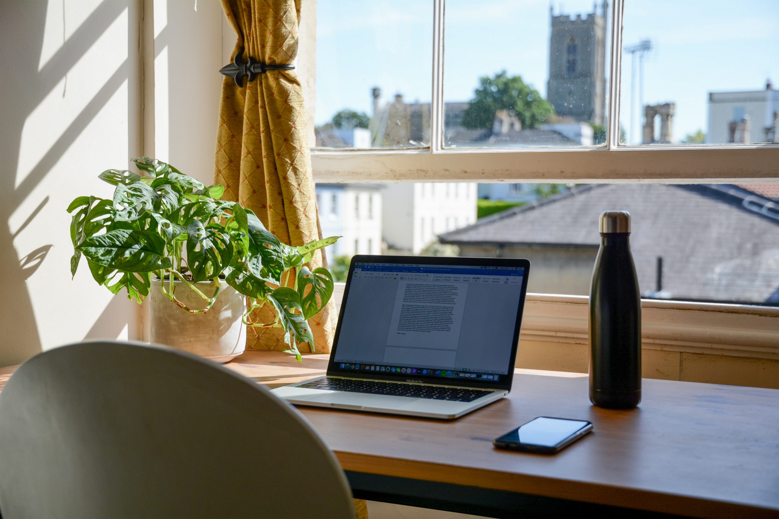 A laptop at a desk by the window, in someones house